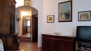 A living room with a television, wooden furniture, and framed pictures on the wall. - Tuscan Charm: Frassini Cottage (Chiusdino)