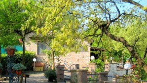 A courtyard with stone walls, potted plants, and a brick pathway. - Tuscan Charm: Frassini Cottage (Chiusdino)