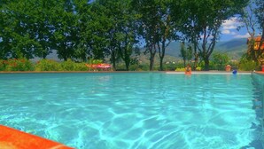 A clear swimming pool surrounded by trees and a view of distant hills. - Tuscan Mansion Getaway (Castelfranco Piandisco)