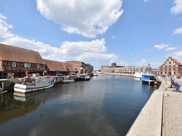 Un canal con barcos amarrados, edificios de arquitectura tradicional y un cielo despejado.