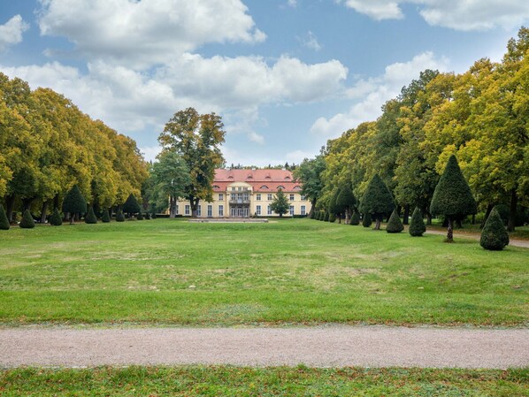 A large, symmetrical building with a central entrance, surrounded by a well-maintained lawn and rows of trees. - Cozy Apartment near Sea in Warin (Warin)
