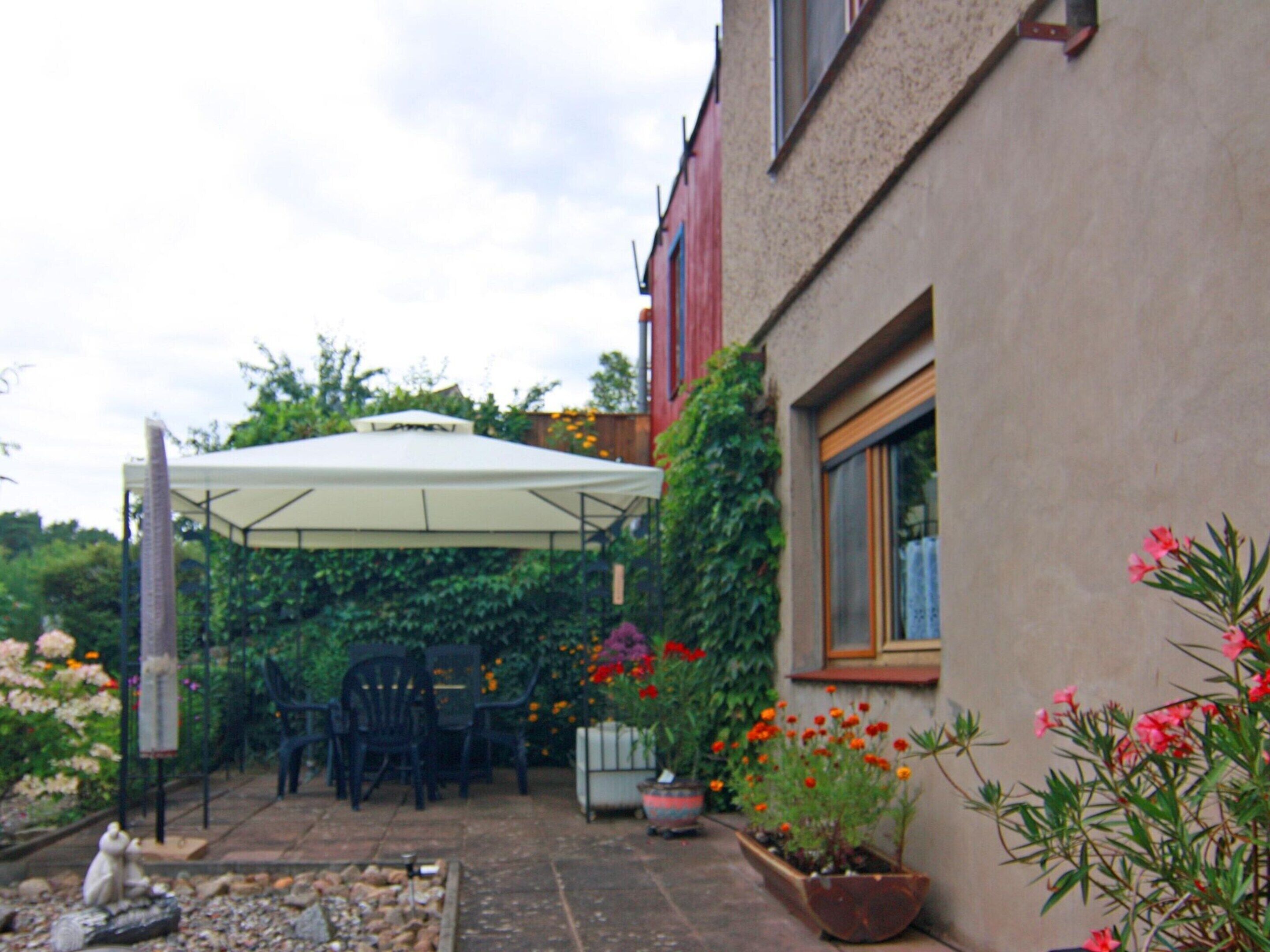 Un patio couvert aménagé avec du mobilier d’extérieur, des plantes en pot et un petit jardin.