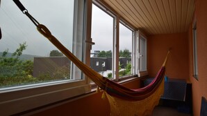 Una habitación con hamaca, ventanas amplias y vistas a edificios.