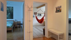 Una habitación con cama, escritorio, sillón colgante y perchero.
