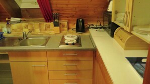 A compact kitchen with a sink, stove, and wooden cabinets. - Ferienhaus, Schwarzwald (Sankt Georgen im Schwarzwald)