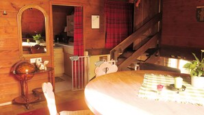 A wooden interior with a round dining table, a chair, a mirror, a staircase, and a red plaid curtain. - Ferienhaus, Schwarzwald (Sankt Georgen im Schwarzwald)