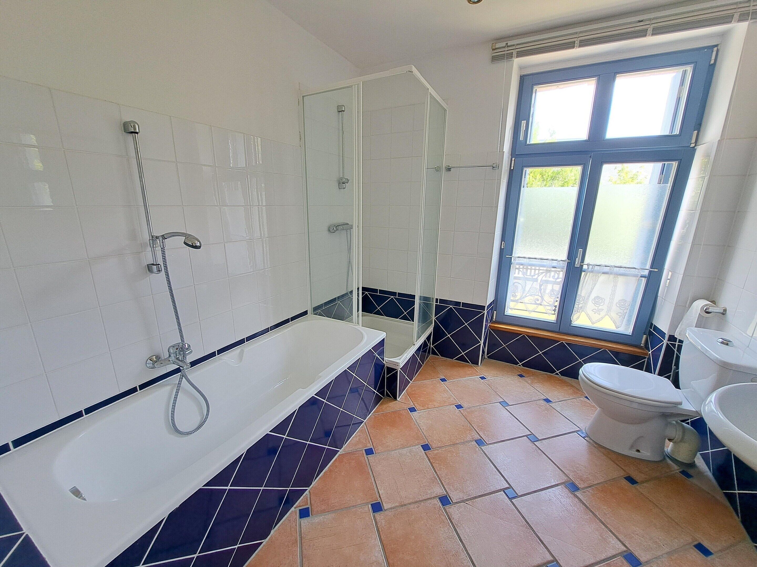 A bathroom with a bathtub, toilet, and shower area.