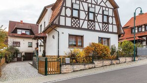 A traditional half-timbered house with a cobblestone driveway and a small garden with autumn foliage. - Holiday Home in Thuringia With Private Terrace, use of a Garden and Pool (Roemhild)