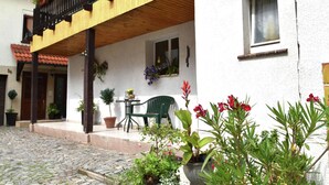 A building with a wooden balcony, potted plants, and a stone-paved courtyard. - Holiday Home in Thuringia With Private Terrace, use of a Garden and Pool (Roemhild)