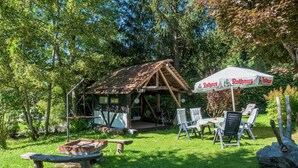 A rustic wooden structure with a porch, outdoor seating, and a table. - Ferienwohnung in Gutenbach (Guetenbach)