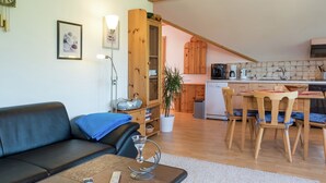 A living room with a sofa, a coffee table, and a dining area with chairs and a table. - Ferienwohnung in Gutenbach (Guetenbach)
