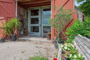 A red building with a wooden bench and potted plants.
