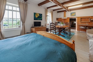 A bedroom with a bed, a TV, a dining table with chairs, a kitchen area, and a view of the outdoors. - Farmhouse by Lauwers River With Rowing Boat (Burum)