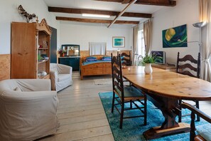 A room with a wooden bed, a dining table with chairs, a wooden cabinet, and a mirror. - Farmhouse by Lauwers River With Rowing Boat (Burum)