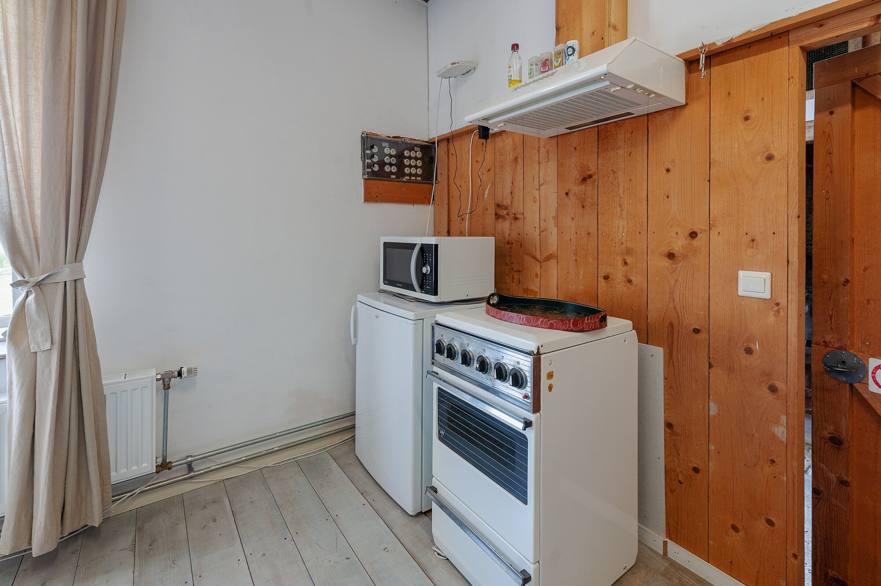 A compact kitchen with a microwave, oven, and a small refrigerator.