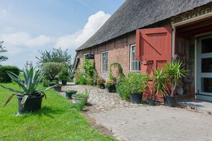 A brick building with a red door, a cobblestone pathway, and potted plants.