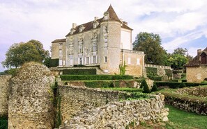 A historic stone building with a central tower, surrounded by well-maintained gardens and a stone wall. - Cottage in Bourgnac With Whirlpool (Bourgnac)