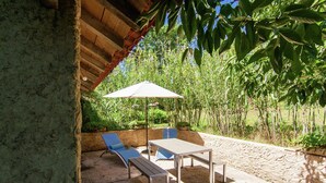 An outdoor patio with a table and two chairs, a bench, and a large umbrella.