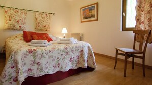 A bedroom with a bed, a chair, a lamp, and a painting on the wall.