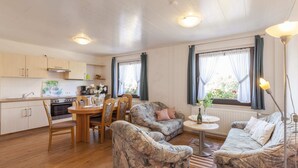 A cozy living room with a sofa, chairs, a dining table, and a kitchen area. - Hillside Cottage Near Winterberg (Hallenberg)