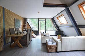 A modern living room with a dining area, a white sofa, and a wooden dining table. - Pet-friendly Getaway (Stramproy)