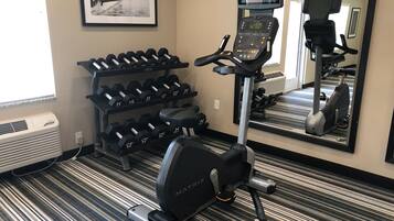A gym with a treadmill, dumbbells, and a mirror.