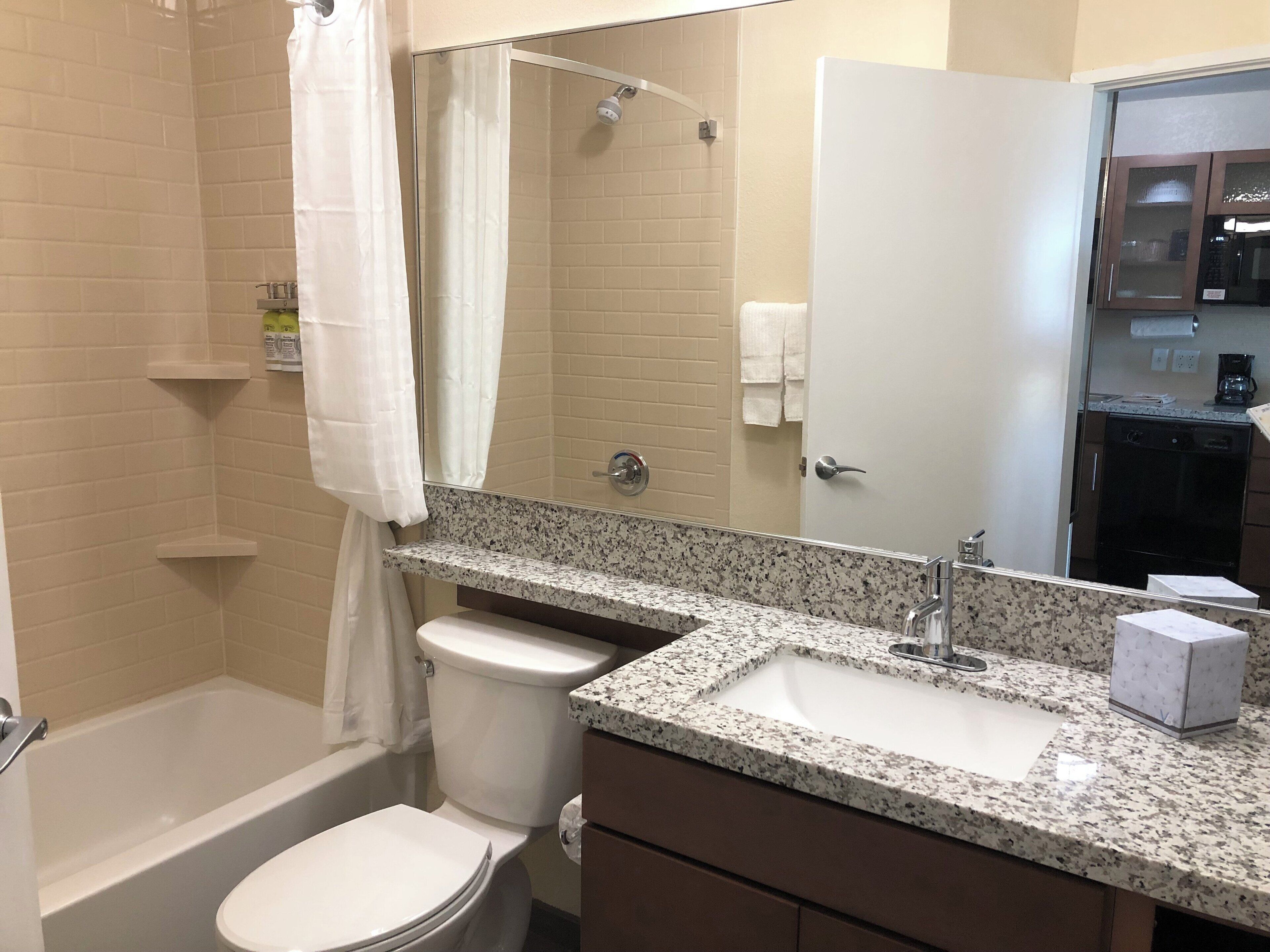 A bathroom with a bathtub, toilet, sink, and a shower area.