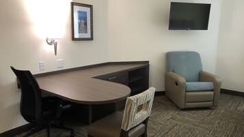 A hotel room with a desk, office chair, and a lounge chair.