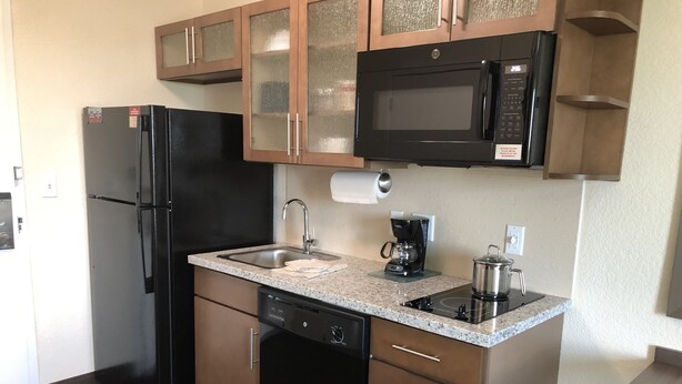 A compact kitchen with a refrigerator, microwave, coffee maker, sink, and dishwasher. - Candlewood Suites Panama City Beach Pier by IHG (Panama City Beach)
