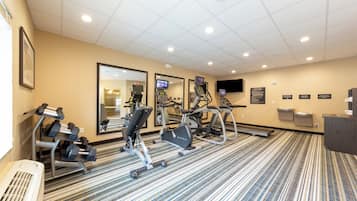 Centro de ginástica do hotel com máquinas de cardio, halteres e um espelho.