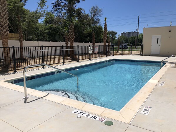 Una piscina rectangular con una escalera metálica y un cartel de prohibido sumergirse.