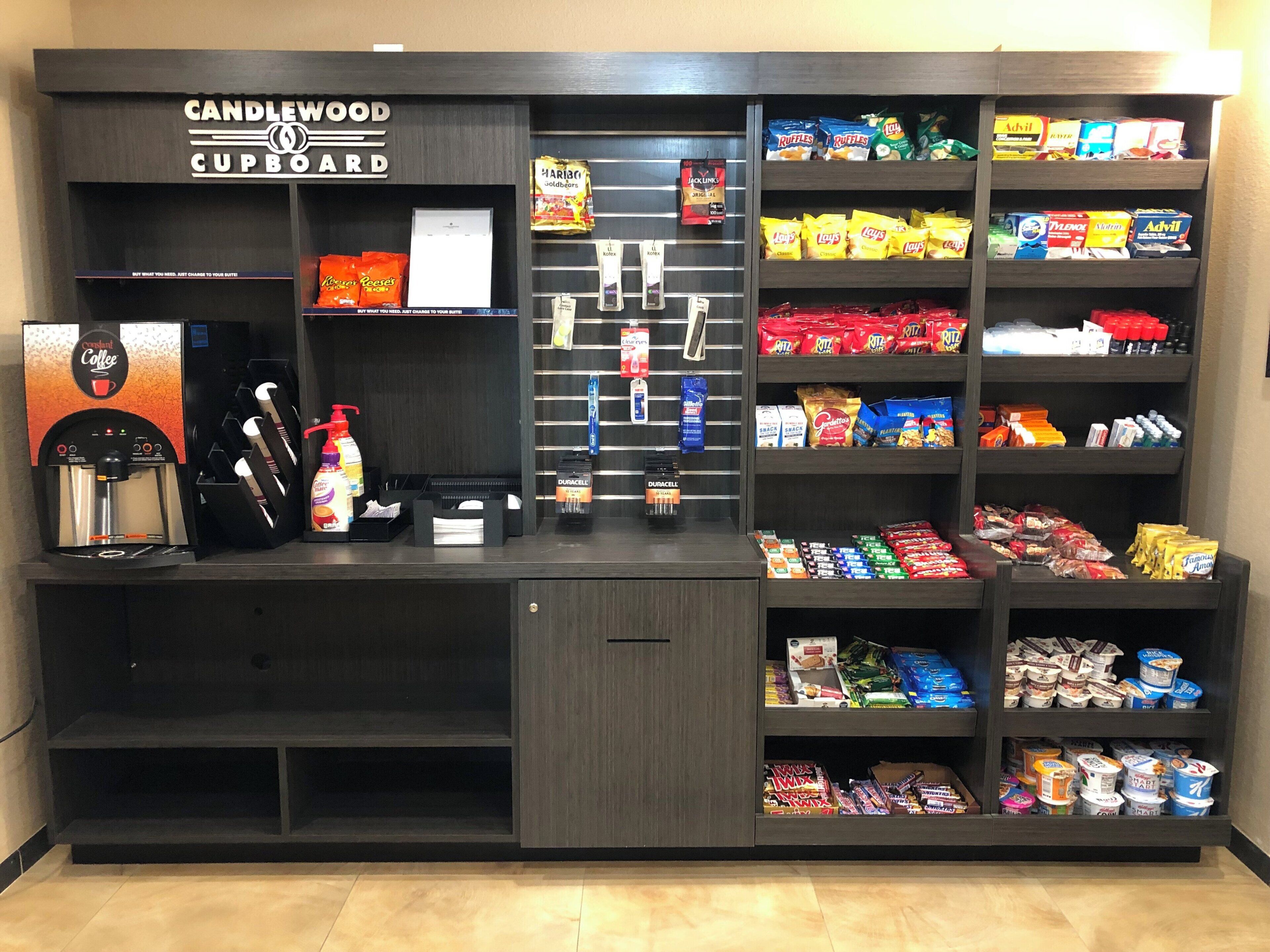 A Candlewood Cupboard with a coffee machine, snacks, and a variety of packaged goods.