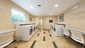 A laundry room with multiple washing machines, a drying rack, and a mirror. - Candlewood Suites Panama City Beach Pier by IHG (Panama City Beach)