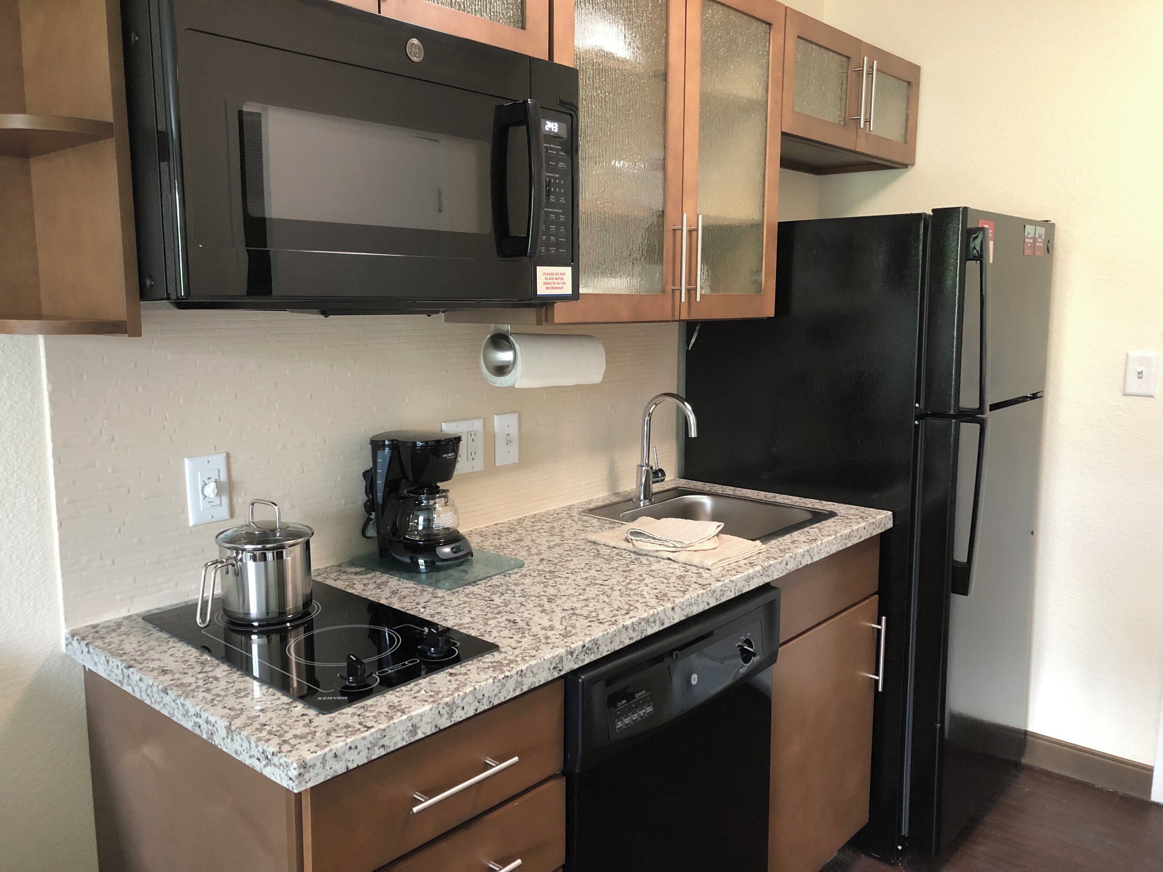 A kitchen with a microwave, coffee maker, sink, dishwasher, and a refrigerator.