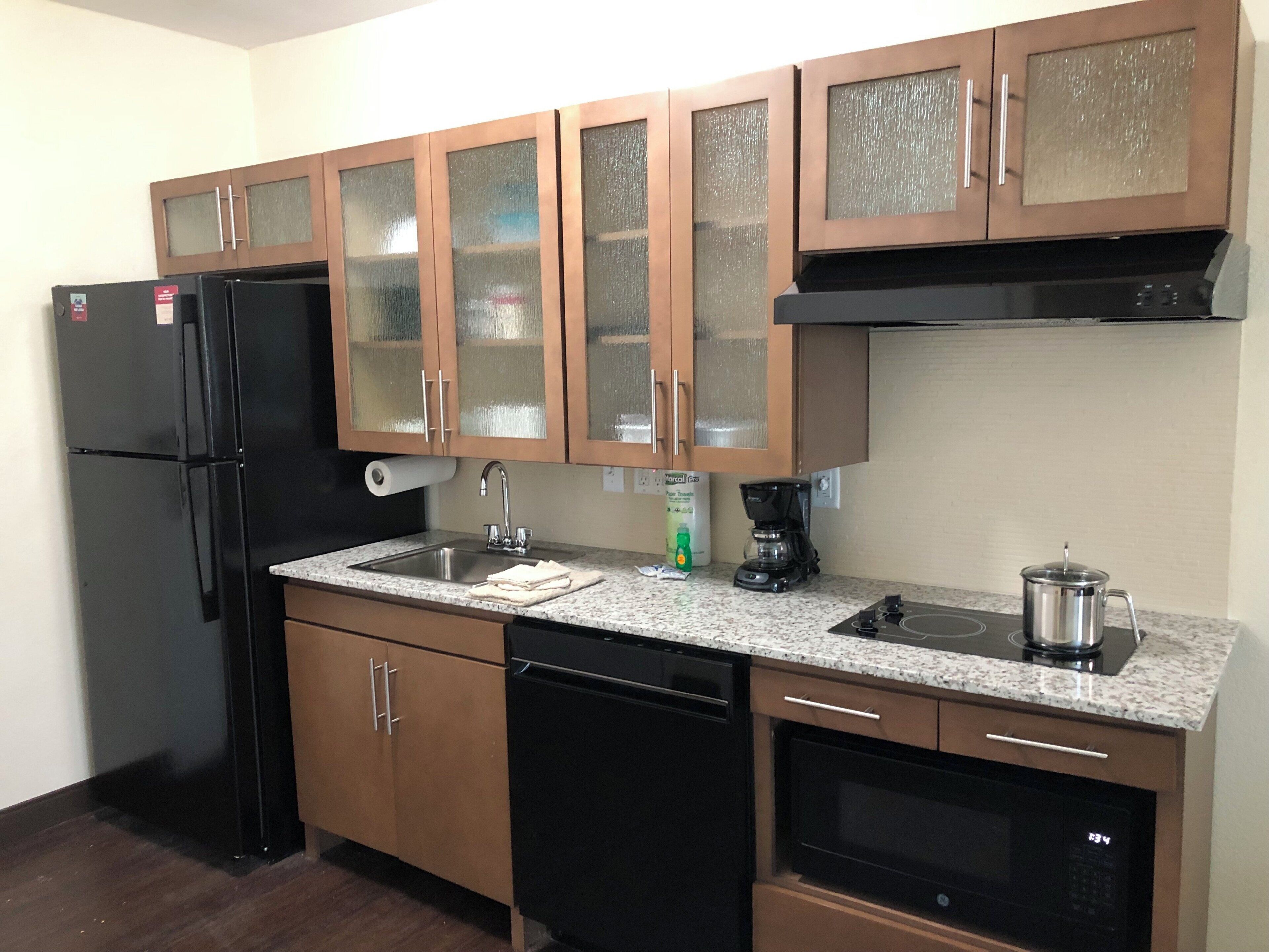 Una cocina equipada con refrigerador, lavavajillas, estufa, microondas y armarios.