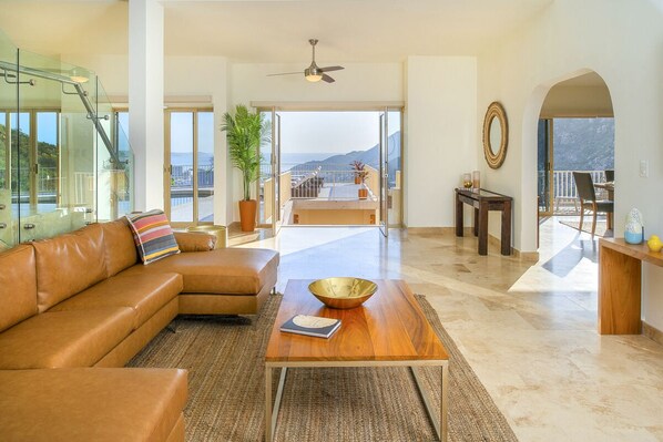 A spacious living room with a leather sofa, a wooden coffee table, and a view of the balcony.
