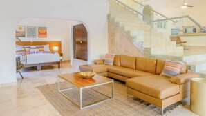 Ein modernes Wohnzimmer mit Sofa, Couchtisch und einer Treppe mit Glasgeländern.