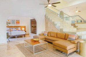 A modern living room with a sofa, coffee table, and a staircase with glass railings.