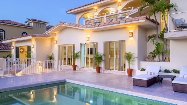 Ein Poolbereich mit klarem Pool, Sitzgelegenheiten im Freien und einem Gebäude mit Balkon.
