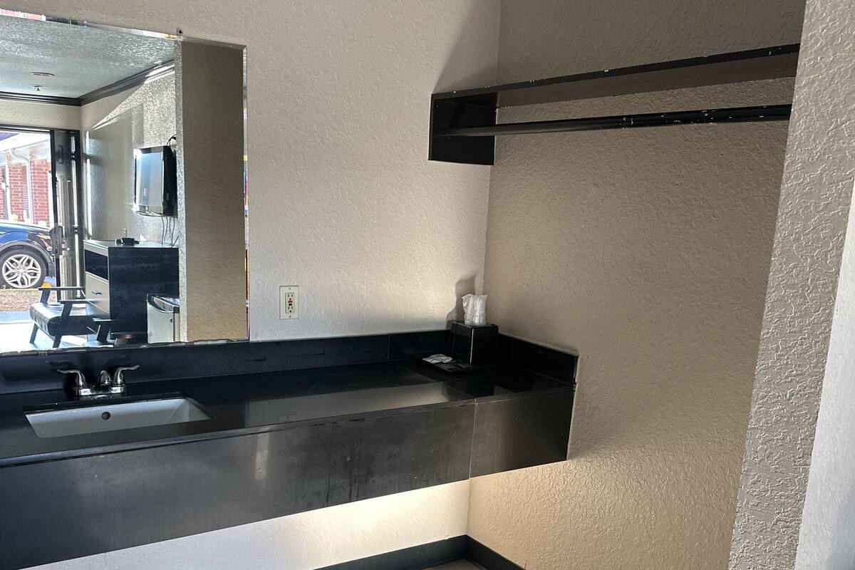 A modern bathroom with a large mirror, a black countertop, and a wooden floor.