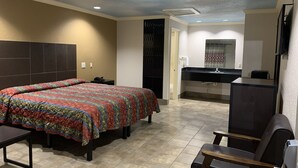 A hotel room with a bed, a desk, a chair, a bathroom with a sink, and a mirror. - Luxury Inn and Suites (Houston)