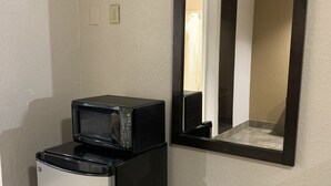 A compact kitchenette with a microwave and a small refrigerator. - Luxury Inn and Suites (Houston)