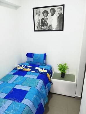 A bedroom with a bed covered in a blue and white quilt, a framed photo on the wall, and a small potted plant on a bedside table. - Pet Friendly Apart(9 Person max)+Pool+Grill+Billiards+Gym (Lince)
