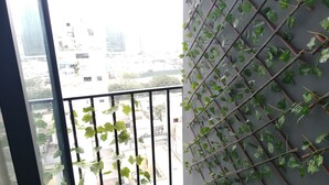 A balcony with a view of buildings and a wall with climbing plants. - Pet Friendly Apart(9 Person max)+Pool+Grill+Billiards+Gym (Lince)