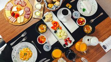 Desayuno con diversas comidas, bebidas y utensilios sobre una mesa.