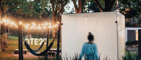 A person sitting on a bench in front of a white sign with the text "OTE20".