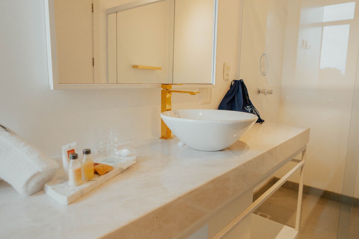 Een badkamer met een witte wastafel, een spiegel en een handdoekhouder.