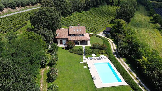 Una vista aerea di una grande proprietà con una casa principale, una piscina e vigneti circostanti.