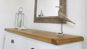 A bathroom vanity with a wooden countertop, a mirror with a rustic frame, and a decorative bird.