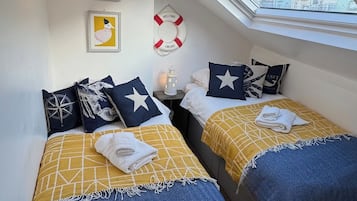 Habitación con dos camas, tragaluz, lámpara de pared y decoración náutica.